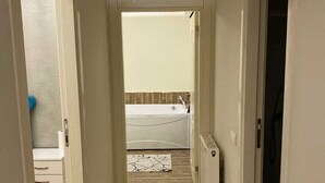 A narrow hallway with a patterned rug, a white radiator, and a ceiling-mounted air conditioner. - Renos Butik Otel (Mersin)