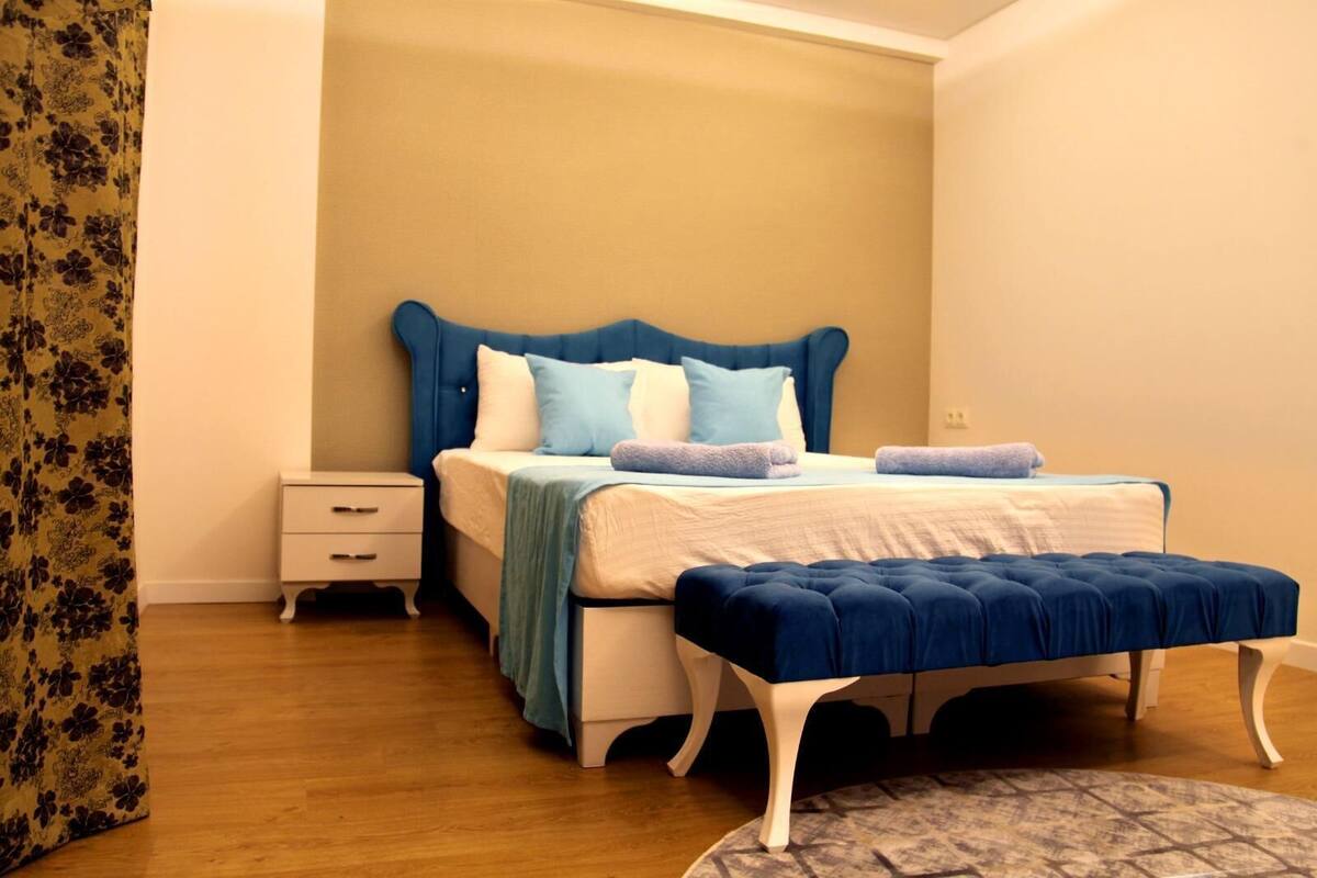 A bedroom with a bed, nightstand, and bench.
