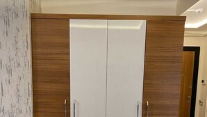 A wardrobe with two doors, a wooden finish, and a white interior. - Renos Butik Otel (Mersin)