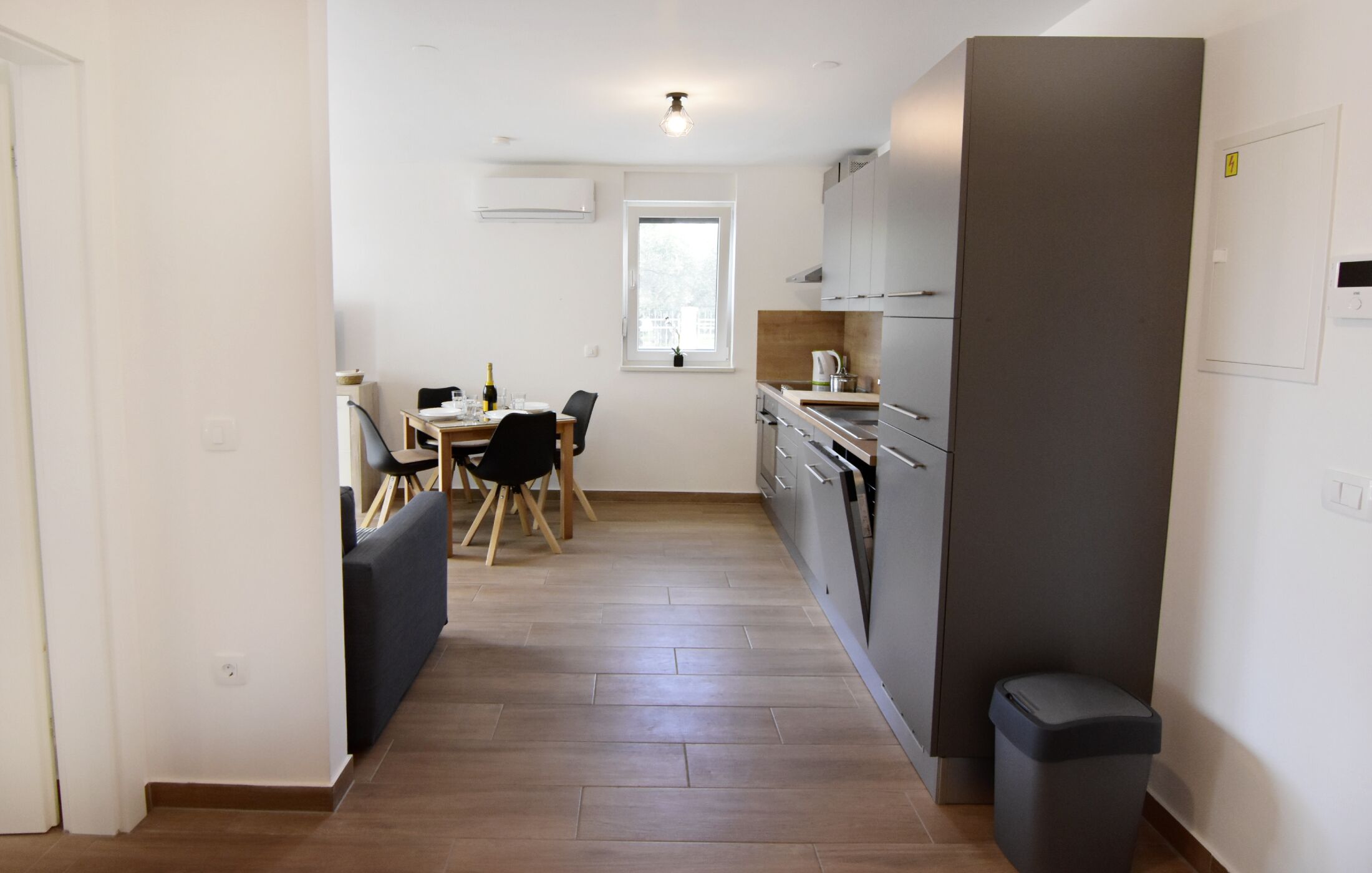 Una cocina compacta con comedor, ventana y un bote de basura.
