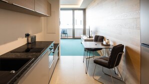 A modern kitchen with a built-in stove, a sink, and a dining area with a table and chairs.