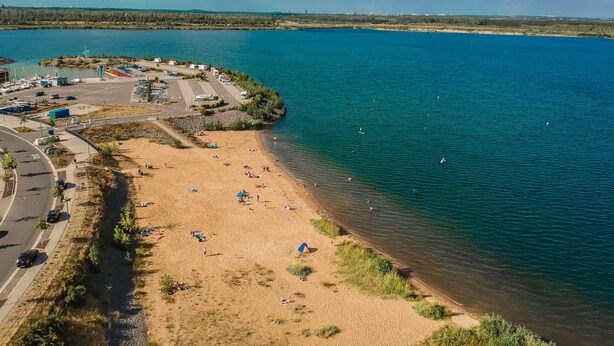 An aerial view of a beach with a parking area and boats.