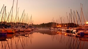 A marina with multiple boats docked, calm water, and a sunset in the background.