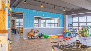 Zona de juegos infantiles con pared azul, suelo de madera y diversos juguetes.
