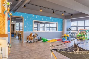 A children's play area with a blue wall, wooden flooring, and various toys. - Geoje Gabaestory Pension (Geoje)