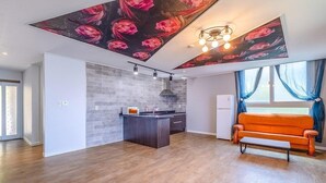 Una cocina moderna con una isla central, un comedor con un banco y una sala de estar con sofá.