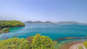 Un paisaje costero con aguas turquesas cristalinas, una playa arenosa y abundante vegetación.