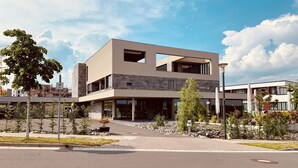 Een modern gebouw met twee verdiepingen, een plat dak, grote ramen en een stenen gevel.