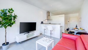 A modern living room with a flat-screen TV, white sofas, a coffee table, and a dining area with a table and chairs. - Residenza Castello Flat With A/C and Garage (Mendrisio)