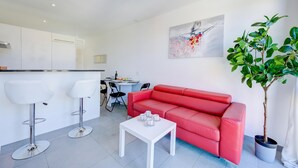 A modern living room with a red sofa, white coffee table, and two white bar stools. - Residenza Castello Flat With A/C and Garage (Mendrisio)