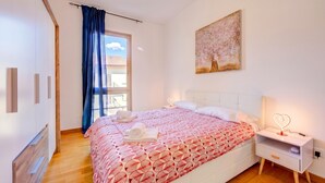 A bedroom with a bed, a nightstand, a painting, and a window with curtains. - Residenza Castello Flat With A/C and Garage (Mendrisio)