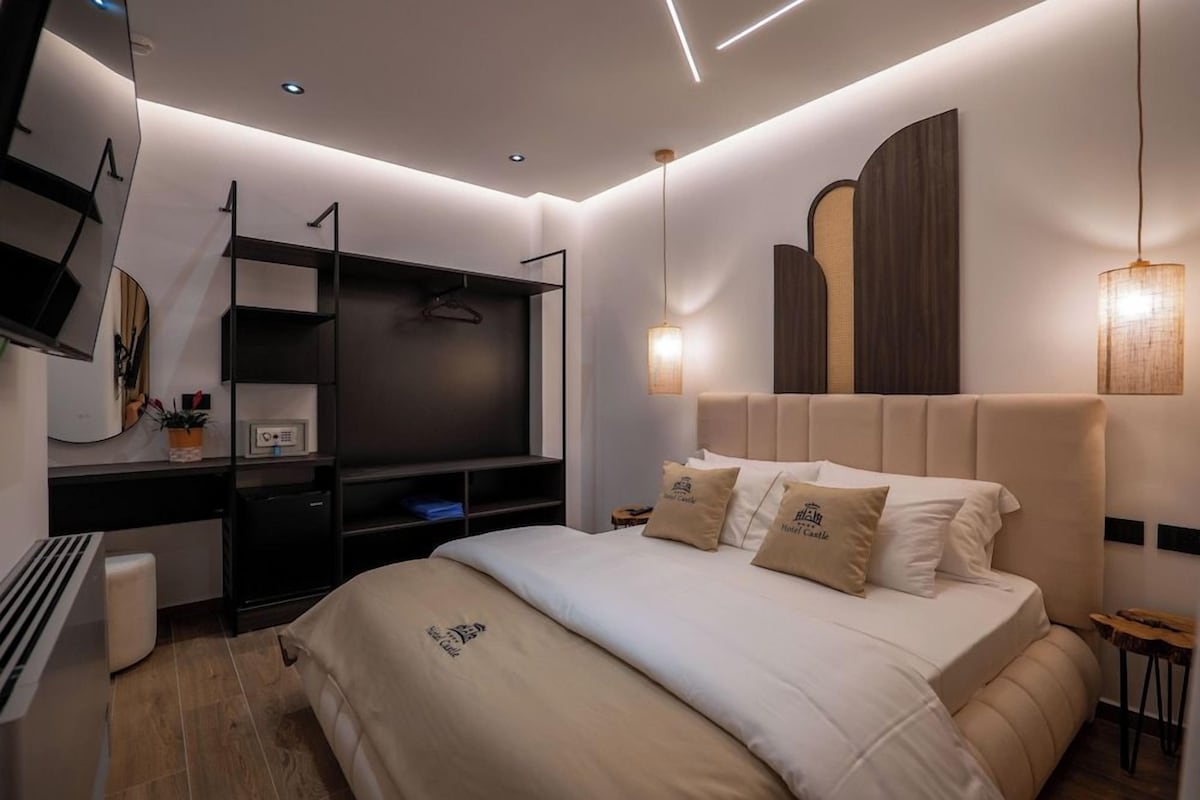 A modern hotel room with a bed, a desk, and a TV.