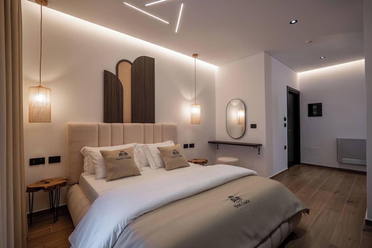 A modern hotel room with a large bed, bedside tables, a mirror, and ambient lighting.