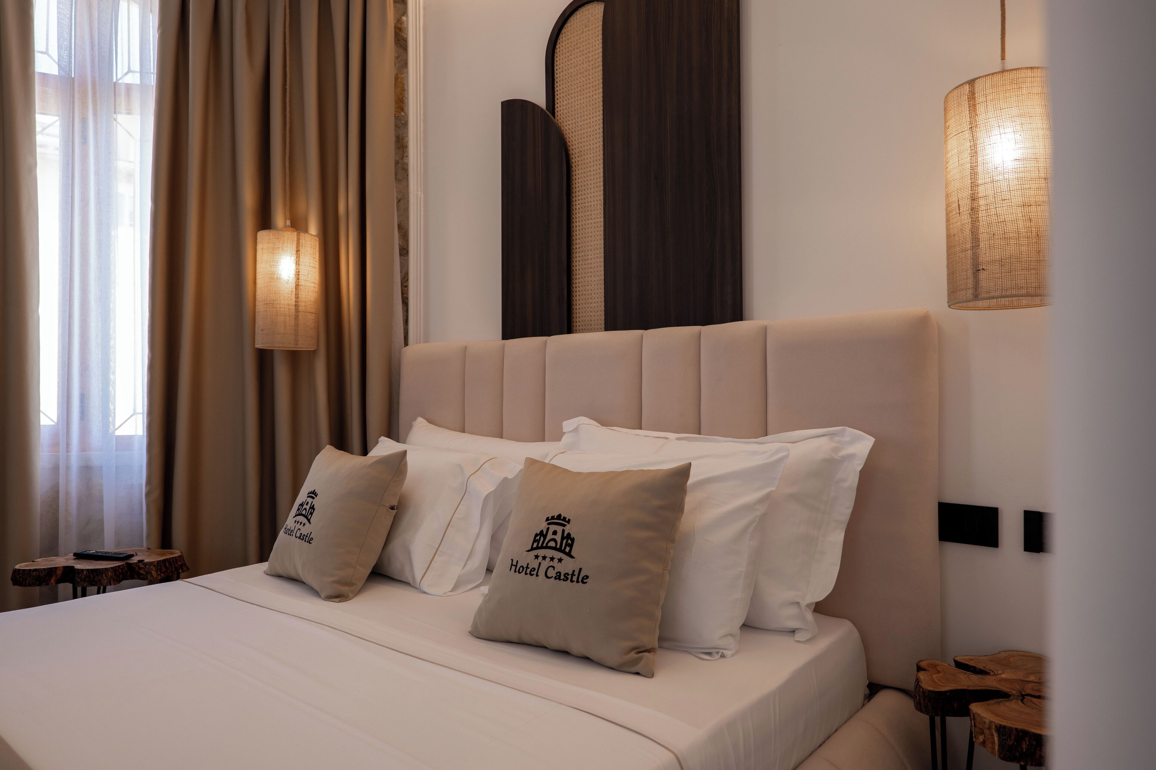 A hotel room with a large bed, two pillows with text, a bedside table, and a wall-mounted lamp.