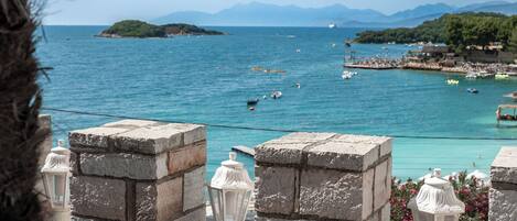A stone wall with a view of a coastal area, including a body of water and distant islands.