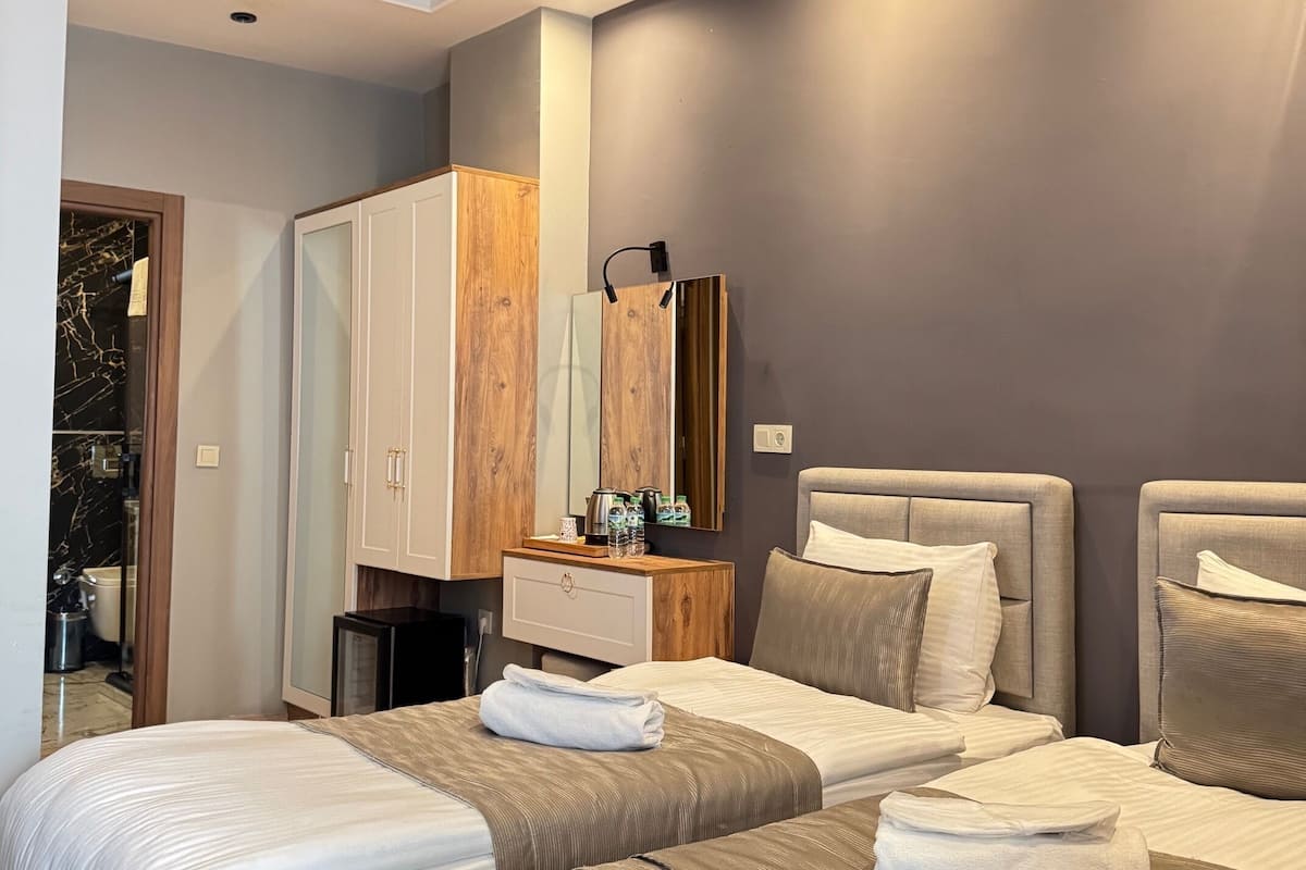 A modern hotel room with two beds, a wooden ceiling, and a minibar.