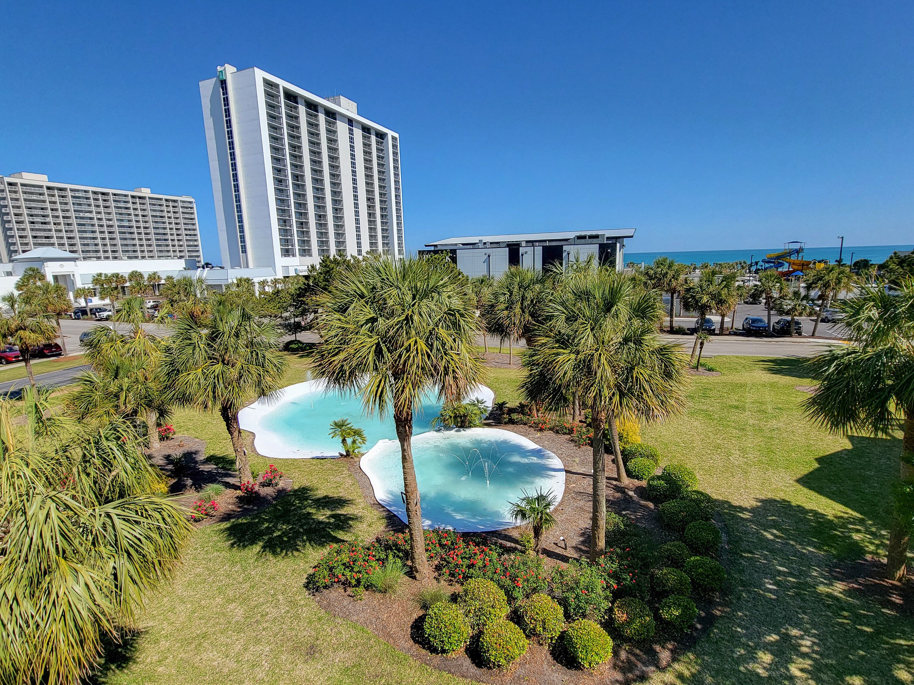 Hotel amb un edifici gran, zona de piscina amb palmeres i vista a l'oceà.