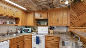 A kitchen with wooden cabinets, a microwave, a stove, and a sink. - Lake View Access, 3 Decks, King Bed, Fire Pit, Dogwood Canyon (Lampe)
