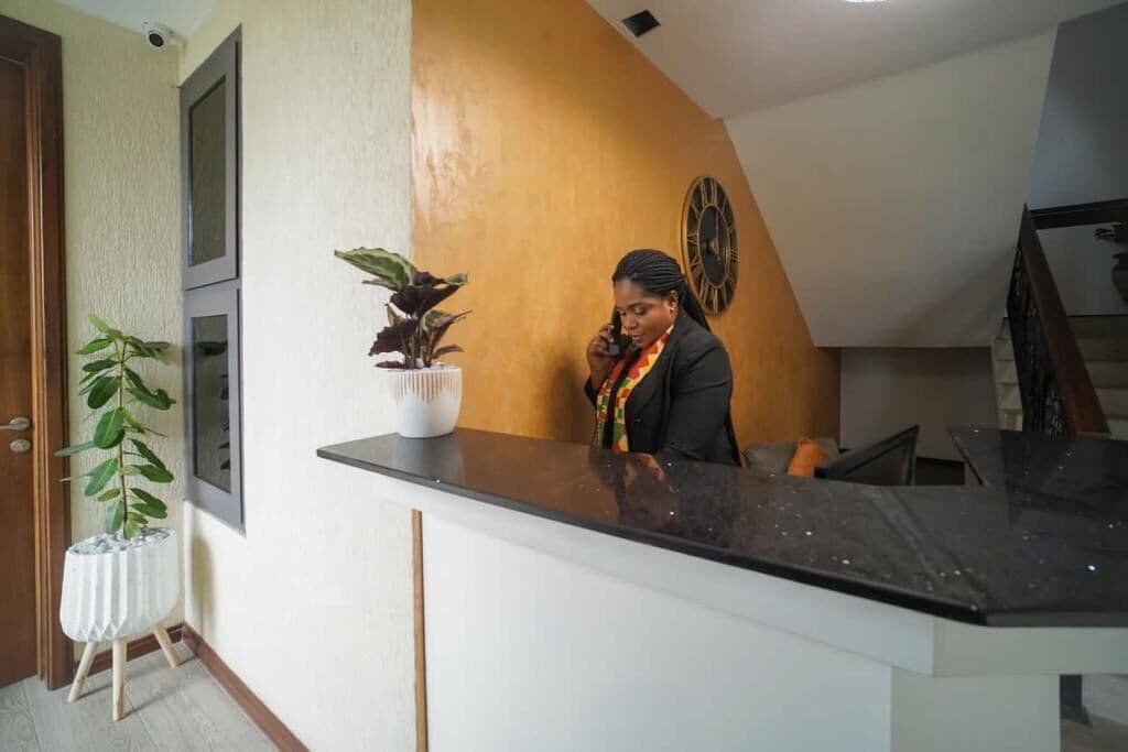 A reception area with a counter, a potted plant, and a wall clock.