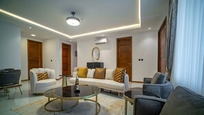 A modern living room with a sofa, armchairs, a coffee table, and a TV. - Alexander Palace Hotel Apartment (Amrahia)