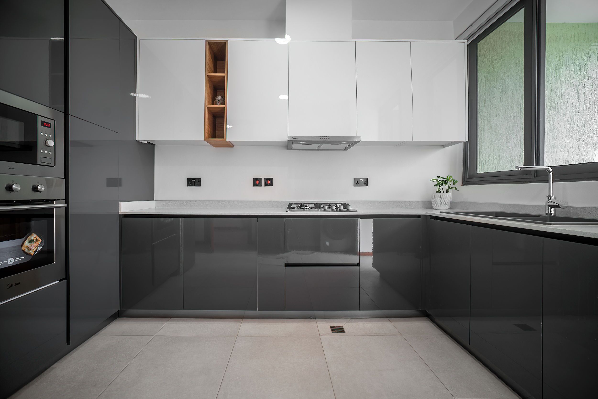 A modern kitchen with dark cabinets, a built-in oven, a microwave, and a stainless steel range hood.