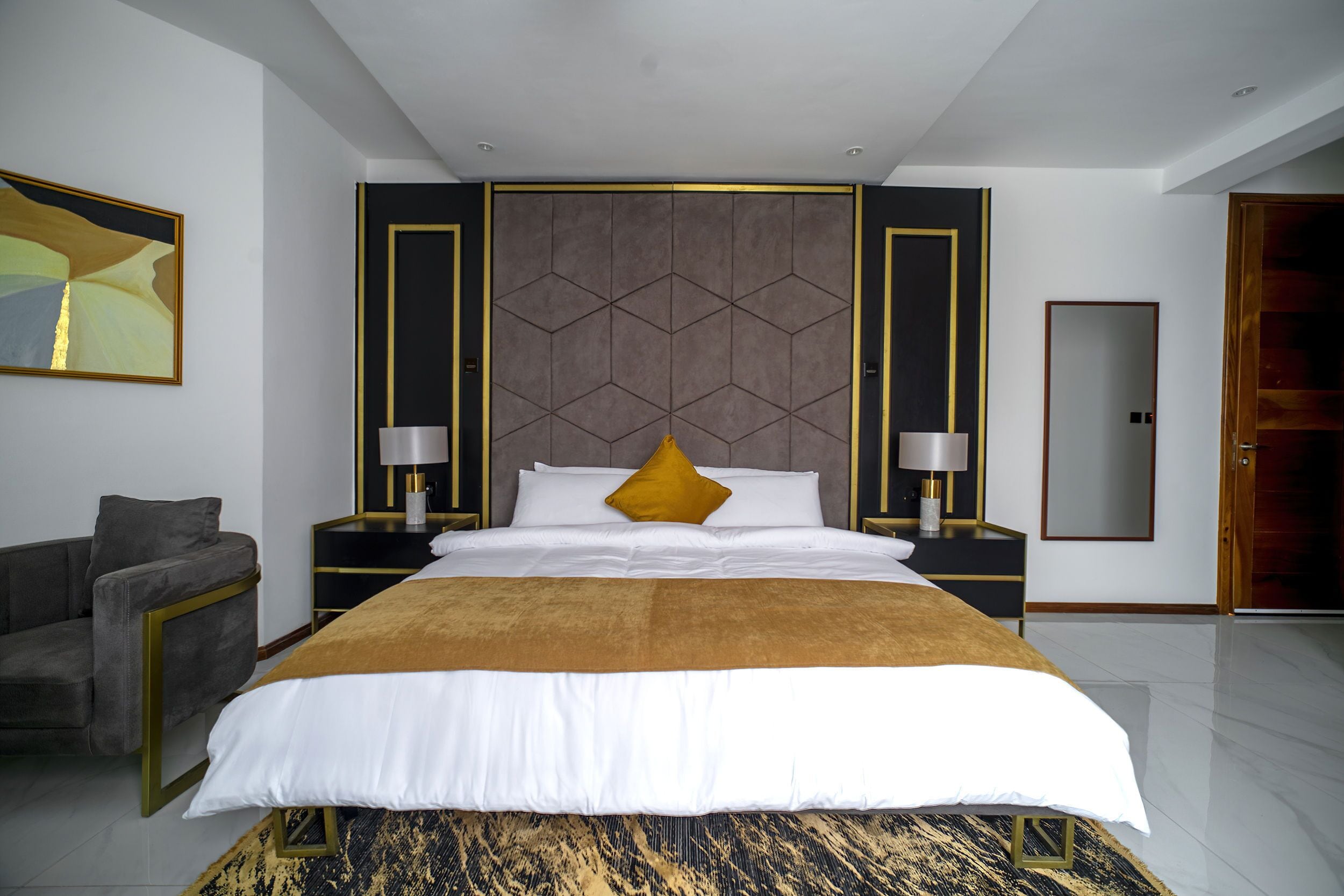 A modern hotel room with a large bed, a sofa, and a mirror.