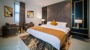 A modern hotel room with a large bed, a sofa, a desk, and a chair. - Alexander Palace Hotel Apartment (Amrahia)