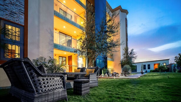 A hotel with outdoor seating and a well-maintained lawn. - Alexander Palace Hotel Apartment (Amrahia)