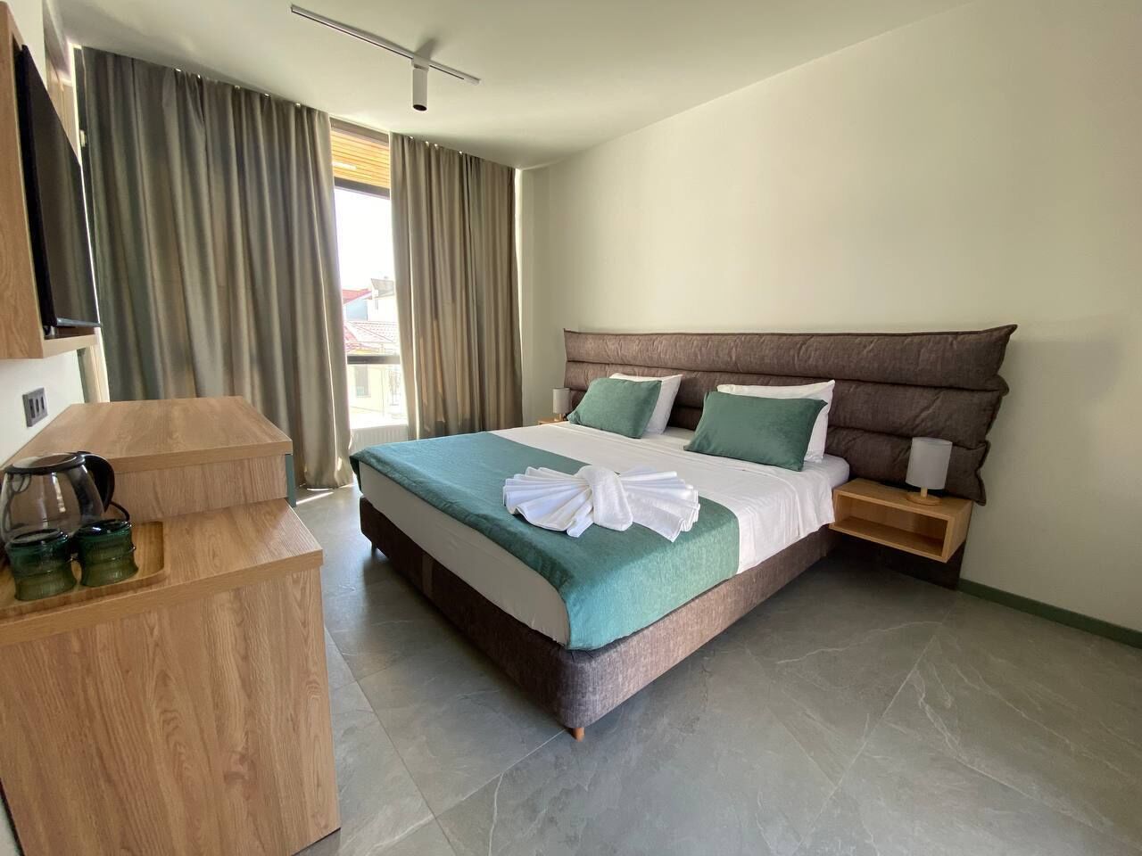 A hotel room with a large bed, a wooden side table, and a TV on a stand.