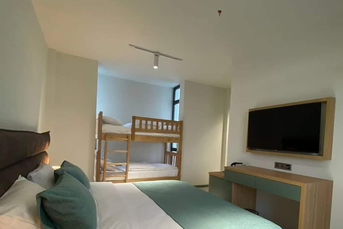 Un dormitorio con literas, un escritorio, un televisor y una cama con almohadas.