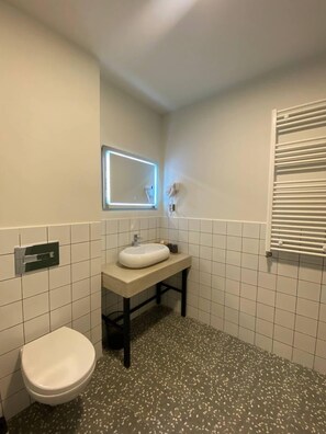 A small bathroom with a white toilet, a sink with a mirror above it, and a towel rack. - H2O Ureki (Ureki)
