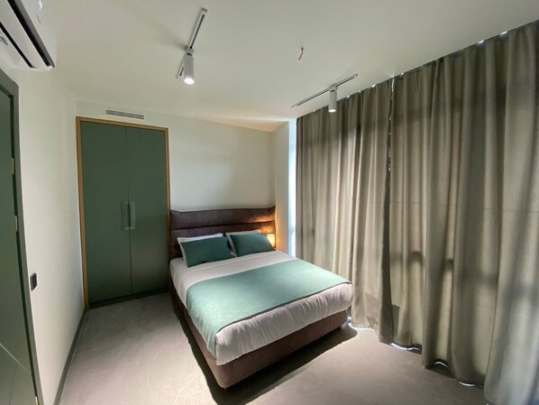 Un dormitorio moderno con cama, armario y ventana con cortinas.