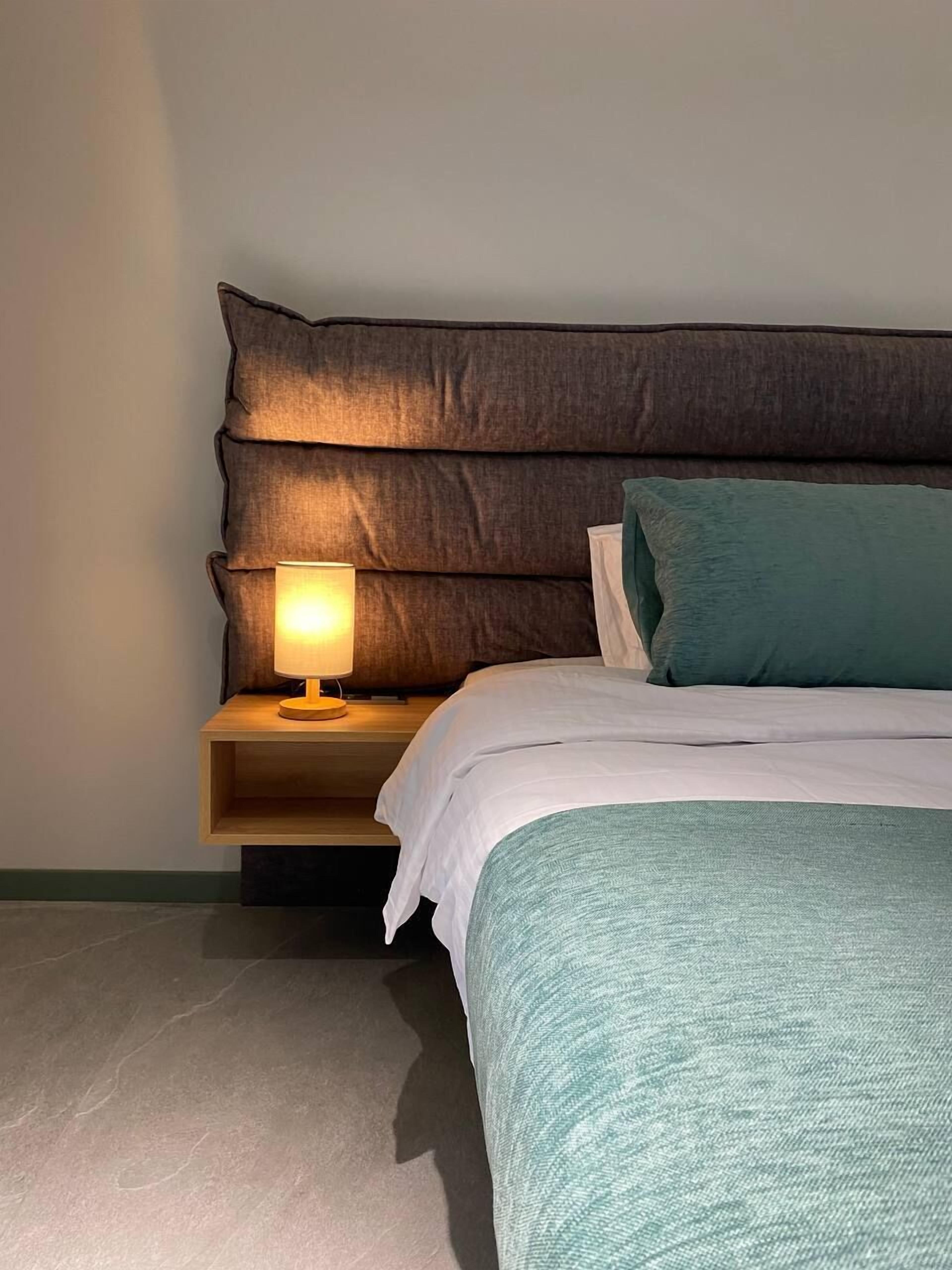 Un dormitorio con cama, mesita de noche y cabecero.
