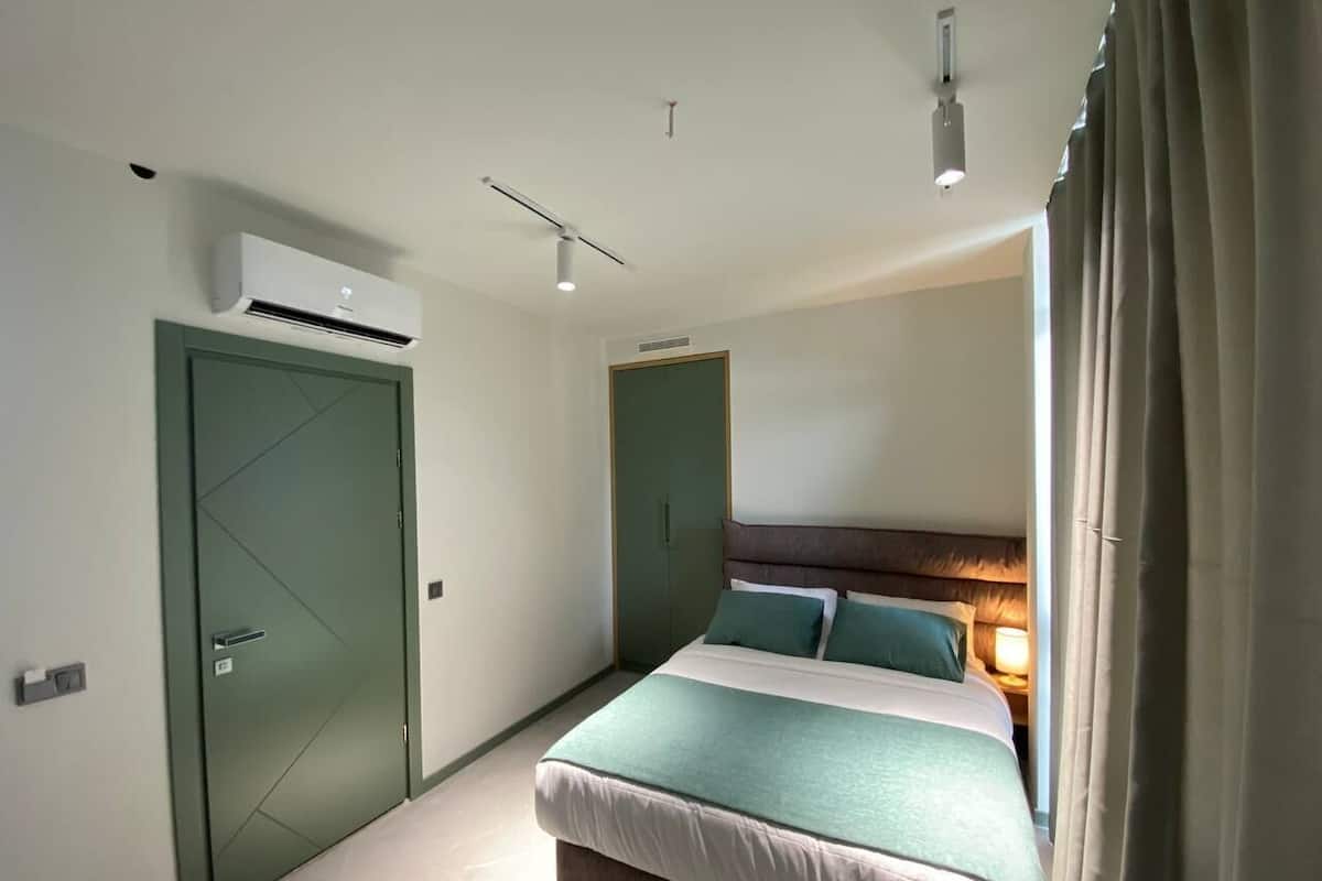 Un dormitorio con cama, mesita de noche, lámpara, aire acondicionado y armario.