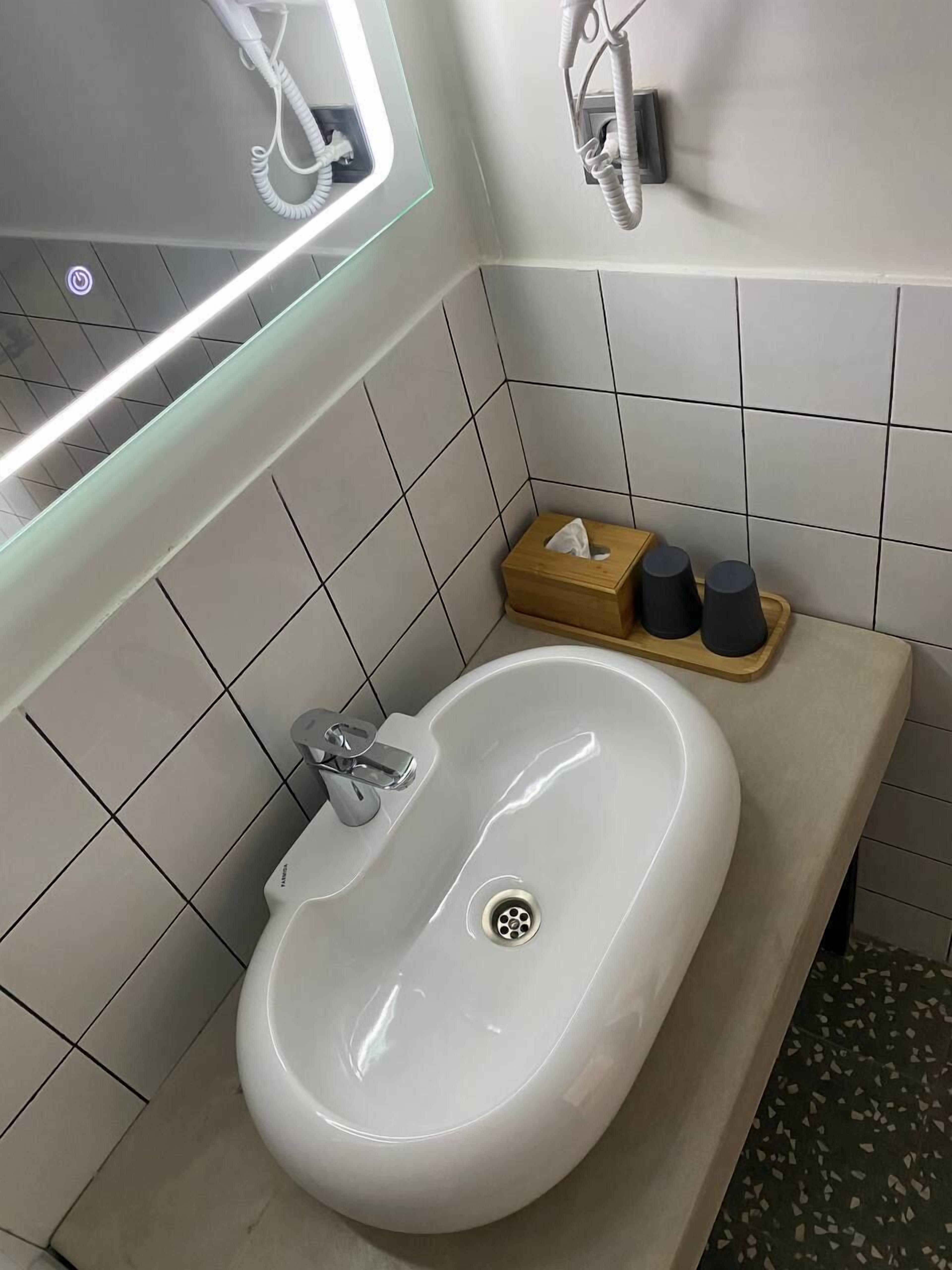 A bathroom with a white sink, a mirror, and a tissue box on the counter.