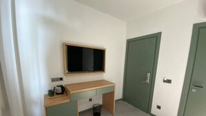 A small room with a wooden desk, a television mounted above it, and a green door. - H2O Ureki (Ureki)