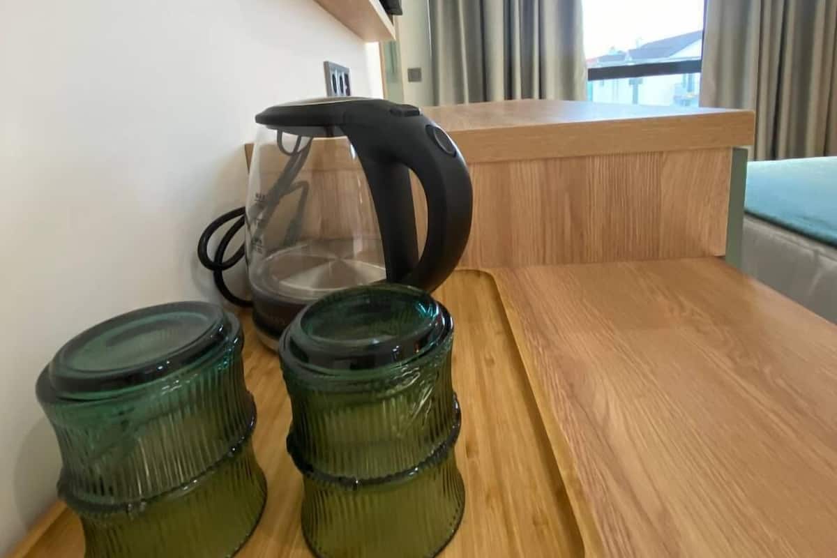 Una cocina con una encimera de madera, dos frascos de vidrio verde y un hervidor.