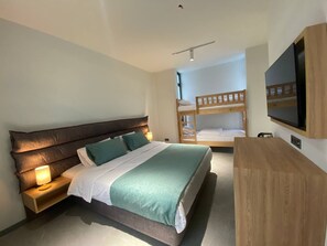 A bedroom with a large bed, a bedside table with a lamp, a bunk bed, and a TV mounted on the wall. - H2O Ureki (Ureki)