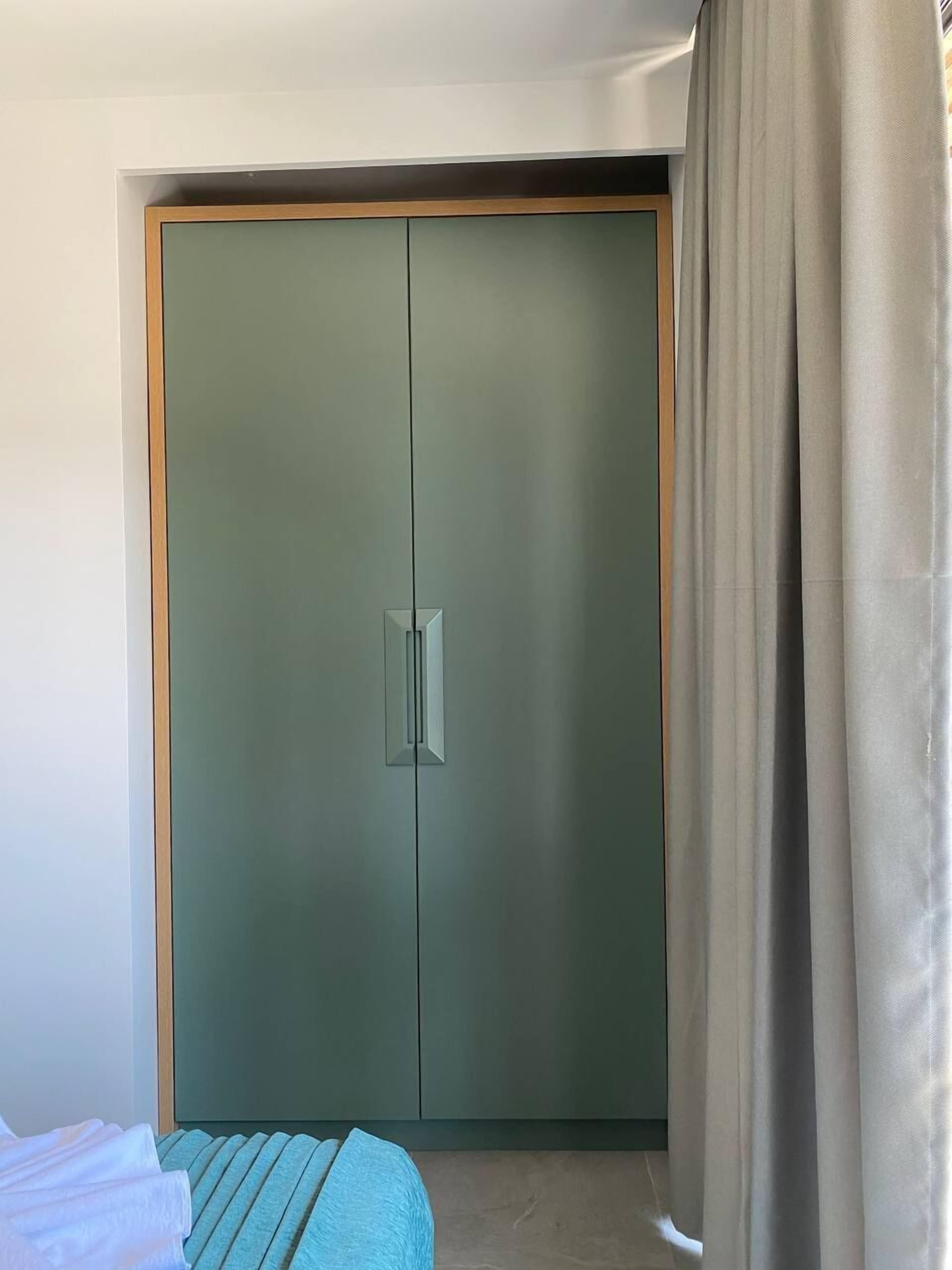 Quarto com cama, guarda-roupa e cortina.