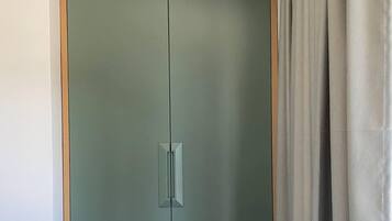 Quarto com cama, guarda-roupa e cortina.