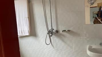 A bathroom with a shower, a sink, and a towel hanging on the wall.