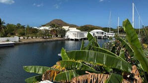 A marina with boats, white buildings, and a mountain in the background. - Luxury Waterfront Villa 431F North Beach (Jolly Harbour)