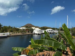 A marina with boats, white buildings, and a mountain in the background.