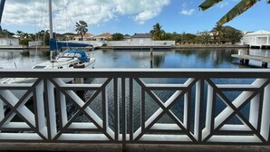 A marina with boats docked, a clear sky, and residential buildings in the background. - Luxury Waterfront Villa 431F North Beach (Jolly Harbour)