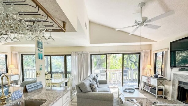 A spacious living area with a kitchen, a sofa, a dining table, and a fireplace. - Beachside Luxury Villa, Balcony Views! Hilton Head (Hilton Head Island)