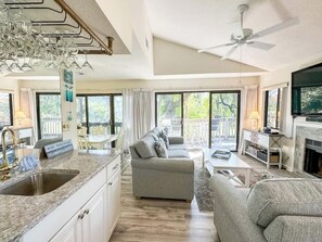 Amplia sala de estar con cocina, sofá, mesa de comedor y chimenea.