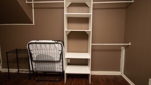 Une pièce avec une étagère blanche adossée à un mur marron, un présentoir en métal noir recouvert d’une housse blanche et un plancher en bois.