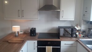 Une cuisine moderne avec des meubles blancs, un grille-pain noir, une bouilloire et une machine à café.