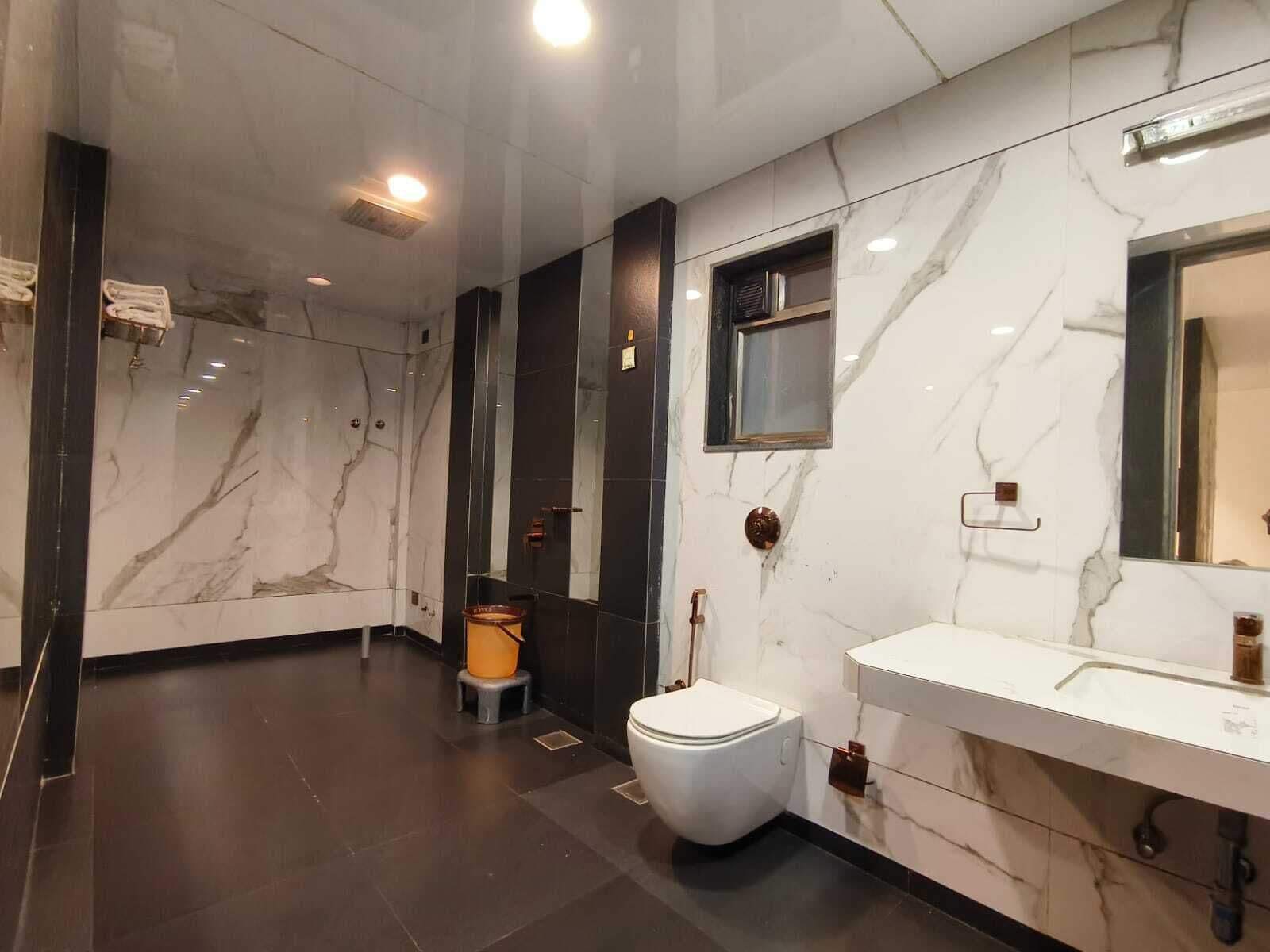 A modern bathroom with a marble vanity, a toilet, and a shower area.