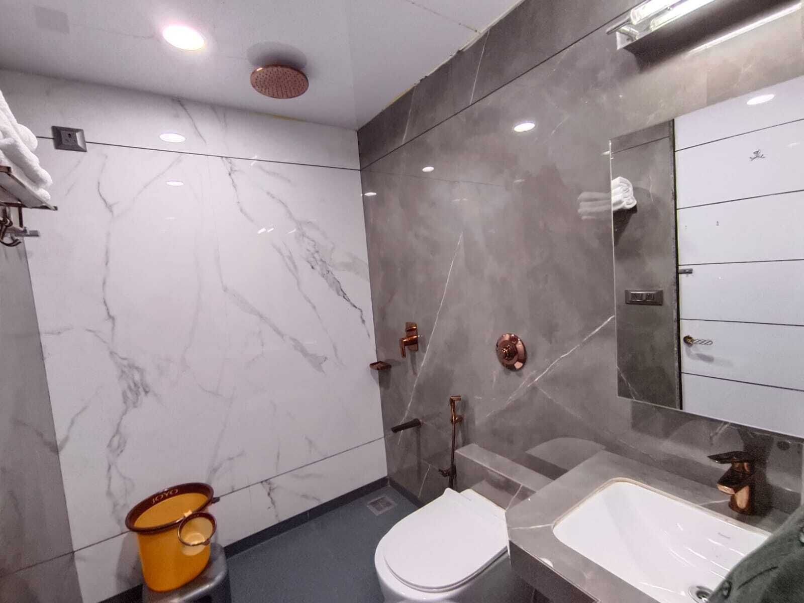 A modern bathroom with a marble floor, a white toilet, a sink, and a mirror.